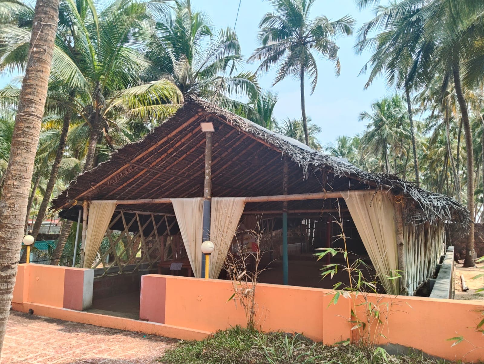 Open-air thatched pavilion and relaxation shala surrounded by palm trees